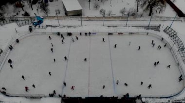 İnsanların buz pateni yaptığı kış paten pistinin insansız hava aracı görüntüsü. İnsanlar Kuzey Avrupa 'da bir hokey stadyumunda kayıyorlar. Sumy şehrindeki buz pateni pistinde insanlar eğleniyor..