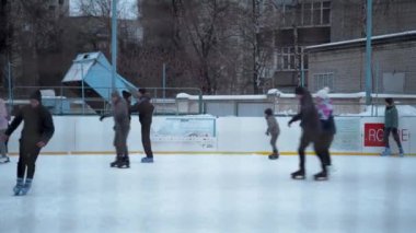 İnsanlar Kuzey Avrupa 'da bir hokey stadyumunda kayıyorlar. İnsanlar Sumy, Ukrayna 'daki buz pateni pistinde eğleniyor. Zincirli bir tel örgüden bak