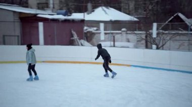 İnsanlar Kuzey Avrupa 'da bir hokey stadyumunda kayıyorlar. İnsanlar Sumy, Ukrayna 'daki buz pateni pistinde eğleniyor. Zincirli bir tel örgüden bak