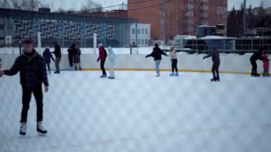 İnsanlar Kuzey Avrupa 'da bir hokey stadyumunda kayıyorlar. İnsanlar Sumy, Ukrayna 'daki buz pateni pistinde eğleniyor. Zincirli bir tel örgüden bak