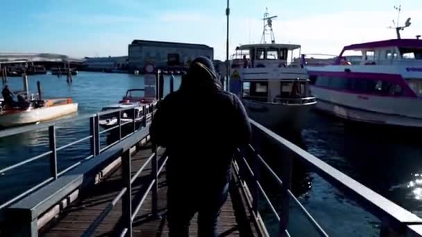 男はイタリアのヴェネツィアに向かう船に向かう イタリアのヴェネツィア港の桟橋で船に乗る — ストック動画