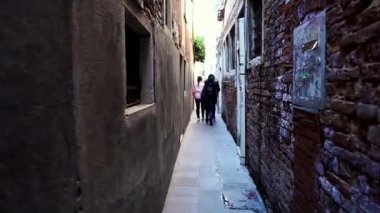 İtalya, Venedik 'te renkli bir cadde. Venedik 'in merkezinde kafeler, restoranlar ve hediyelik eşya dükkanları olan bir cadde. İnsanlar Venedik caddesinde yürüyor.