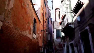 İtalya, Venedik 'te renkli bir cadde. İnsanlar Venedik 'i geziyor. İtalya 'da turistler Venedik' in dar sokakları boyunca yürüyorlar.