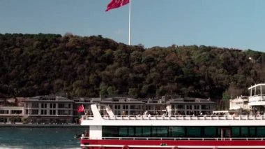 Türkiye 'nin İstanbul kentindeki yeşil ormanlık tepede bir Türk bayrağı. İstanbul 'da İstanbul Boğazı' nda görülen Bebek bölgesinde bir Türk bayrağı. Boğaz teknesi gezisi.