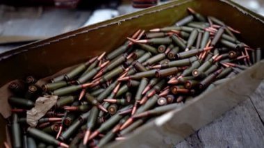 Bir kutu makineli tüfek fişeği yakın plan. Masada otomatik silahlar için bir sürü fişek var.