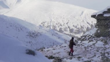 Dağcı açık ve soğuk bir günde kayalık zirvede yürür. Yavaş çekim