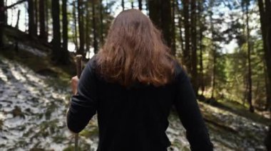 Ormandaki tepenin zirvesinde yürürken uzak bir off-road yolunda yürüyen genç bir kadın.