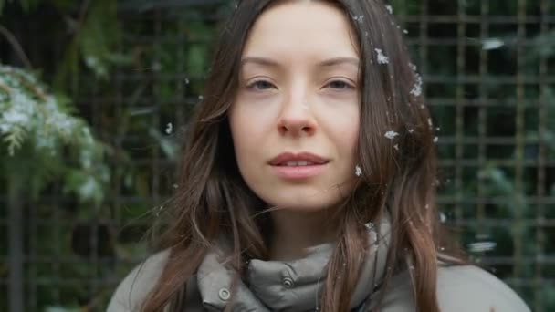 一个年轻的高加索女孩的深褐色头发上长着雪花 她把冬天的雪吹走了 看上去很高兴 — 图库视频影像