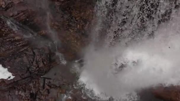川の水に続くドローンのトップビュー空中は岩の間のスプラッシュな新鮮な山の滝に落ちる — ストック動画