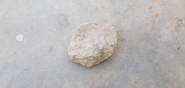closeup view of a single stone isolated on grey cement surface