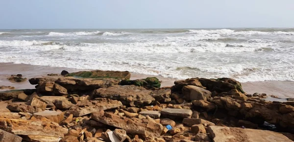 stock image old rocks in front of sea waves and sky