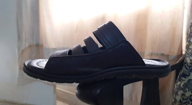 Kahverengi erkek deri sandaletinin kahverengi ahşap arka planda izole edilmiş yakın görüntüsü.