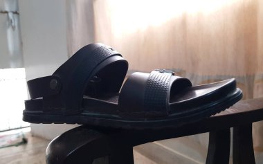 Kahverengi erkek deri sandaletinin kahverengi ahşap arka planda izole edilmiş yakın görüntüsü.