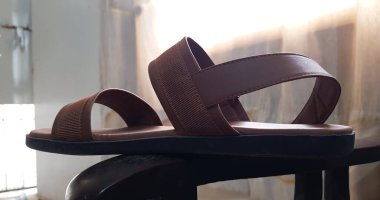 Kahverengi erkek deri sandaletinin kahverengi ahşap arka planda izole edilmiş yakın görüntüsü.