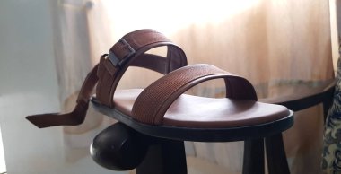 Kahverengi erkek deri sandaletinin kahverengi ahşap arka planda izole edilmiş yakın görüntüsü.