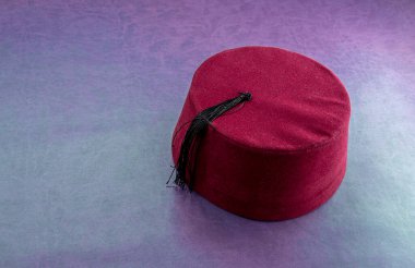 Renkli deri arka planda siyah püsküllü kırmızı şapka.