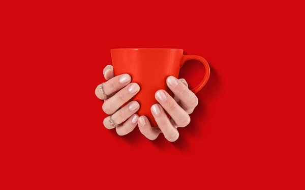 red coffee cup in hands with copy space area.