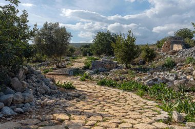 Eski harabelerden geçen taşlı bir yol. Bulutlu ve bulutlu gökyüzü.