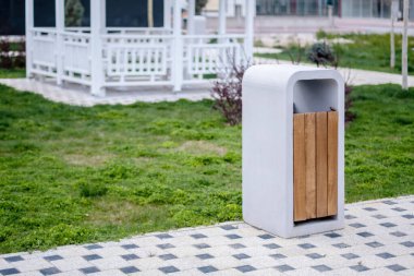 Beton çöp kutusu. Beton ve ahşaptan yapılmış modern bir çöp tenekesi olan huzurlu bir şehir parkı..