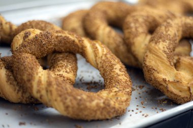 Simit, taze kızarmış Türk çerezi. Taze pişmiş, mükemmel kızartılmış ve tüketilmeye hazır susamlı bir tabağın yakın çekimi..
