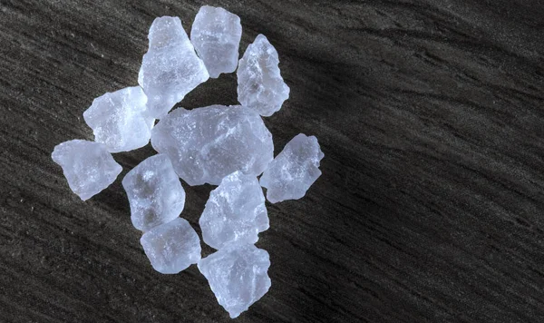Close-up of macro crystals of sea salt or coarse salt isolated on wooden background.