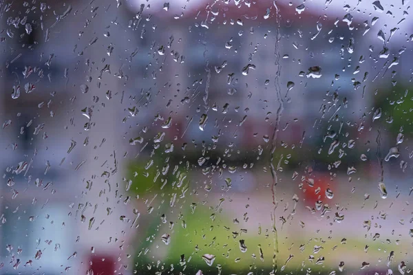 Rain drops on window. Raining in rainy day outside window glass with blurred background.