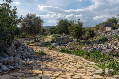Eski harabelerden geçen taşlı bir yol. Bulutlu ve bulutlu gökyüzü.