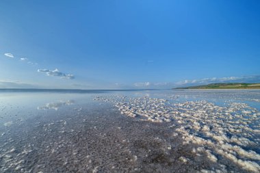 Sonsuz Salt Lake. Sakin mavi gökyüzünün ufka uzanan beyaz tuz oluşumlarıyla buluştuğu sakin bir tuz gölü manzarası. Fotoğraf ultra geniş açılı mercekle çekilmiş.
