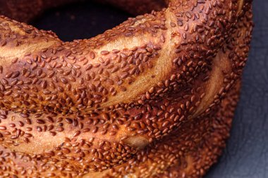 Taze pişmiş susamlı Türk simit ekmeğinin yakın çekimi. Geleneksel çıtır çıtır ve altın simit dokusu detayı. Seçici odak.