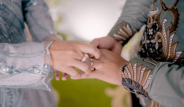 Gelin ve damat elleri yüzüklerle el ele tutuşmuş.