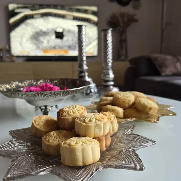 Tatlılar, bayram yemeği için pişirilmiş tatlı kurabiyeler, Mamool ya da Kahk denilen Fitr, oturma odasında Mekke 'yi TV' de gösteriyor..