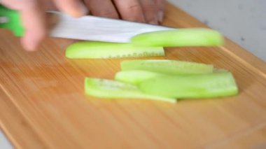 Salatalık, soyulmuş ve kesilmiş bir salatalığın uzun vadede ikiye bölündüğü ve jülyen dilimlendiği yakın çekim videosu.