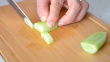 Salatalık, soyulmuş, uzunlamasına kesilmiş bir salatalığın ikiye bölünmüş ve dilimlenmiş halinin videosunu kapat.