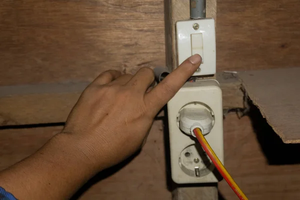 Adamın parmağı elektrik düğmesine basıyor. Lamba soketi tahta duvara yapıştı.