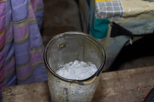 Eldivenli bir kadın, buz küplerini miksere koyar. Tıraşlanmış buzdan ferahlatıcı bir içecek hazırla.