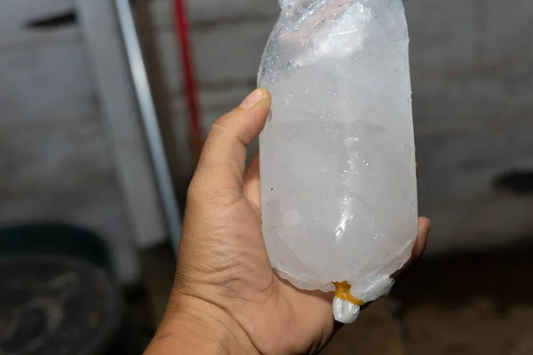 A man holds ice cubes in a plastic bag