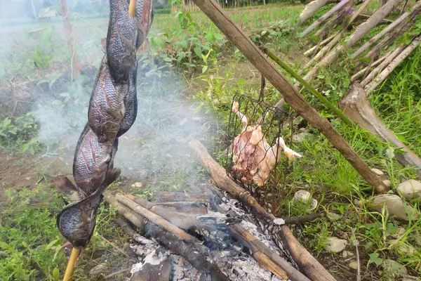 Tavuk ve tilapia yakacak odunların üzerinde kızartılır ve etrafı yabani otlar, kayalar ve tarlalarla çevrilidir..