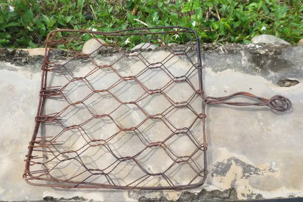 Betonun üzerinde paslı bir ızgara, çimento kaplı bir arka plan ve yeşil çimenler.