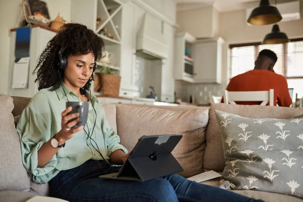 Junge Afrikanerin Mit Kopfhörern Und Tablet Auf Dem Sofa Während lizenzfreie Stockbilder