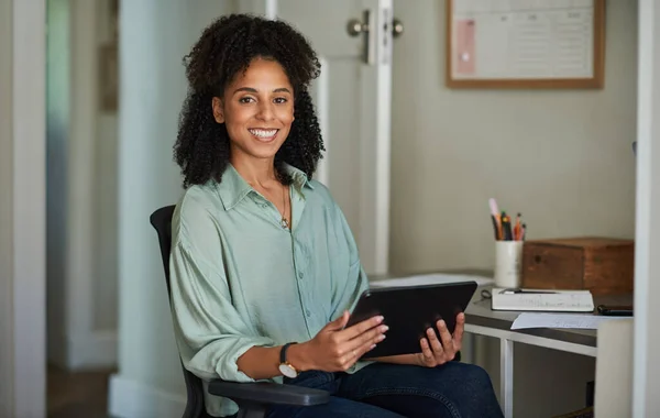 一个面带微笑的非洲女企业家坐在自家办公室椅子上做数码平板电脑的画像 — 图库照片