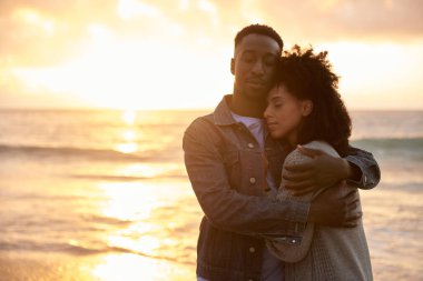 Gün batımında kumlu bir plajda gözleri kapalı duran çok ırklı çifti seven çift.