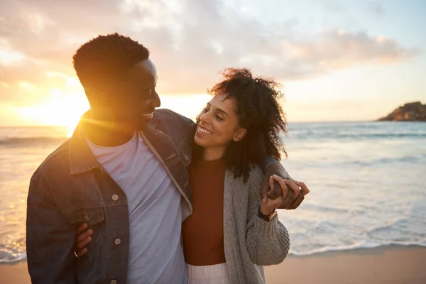 夕暮れ時に砂浜で腕を組んで立っている間 若い多民族のカップルを笑顔で愛情を込めて — ストック写真