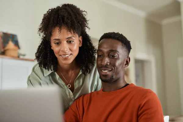 年轻的多种族夫妇一边笑着一边在家里的笔记本电脑上一起网上银行 — 图库照片