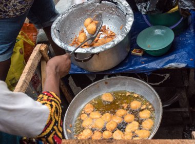 Afrikalı kadın 17 Şubat 2022 'de Lagos, Nijerya' da yol kenarında fasulyeli kek pişiriyor..