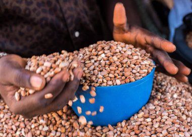 Bir insan Ogun State, Sagamu 'da bir markette satılık bir kaseyle fasulye ölçer.