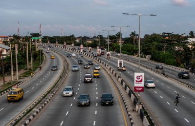1 Eylül 2024 'te Lagos, Nijerya' nın Gbagada bölgesinde gün batımında bir otoyol boyunca hafif trafik