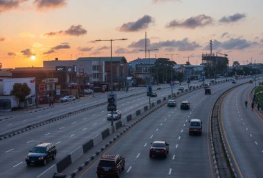 1 Eylül 2024 'te Lagos, Nijerya' nın Gbagada bölgesinde gün batımında bir otoyol boyunca hafif trafik