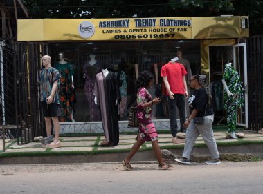 4 Eylül 2024 Çarşamba günü, Ibadan, Oyo State, Nijerya 'da bir moda mağazasının önünden geçen iki bayan....