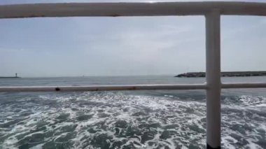 Arka planda, hareket halindeki feribot, deniz feneri ve rıhtımdan deniz dalgaları, İstanbul, Türkiye 'de kamu feribotları, Türkçe adıyla Sehir Hatlari.