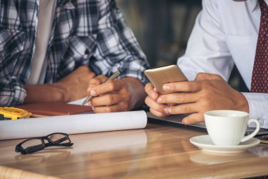 Asyalı mühendis inşaat inşaat müteahhiti kamu çalışanı ortakları toplantı alanında beyin fırtınası yapıyor. Tasarım mühendisi, işçi kaskı masanın üstünde. Mühendis ekip çalışması danışmanlığı